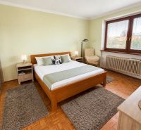Bedroom with a light wall, bed, and floor with wooden decor, in a family house.