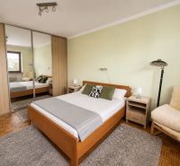 Bedroom with a bed, wardrobe, and wooden decor flooring in a family house.