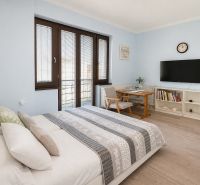 Bedroom in a family house with a bed, TV on the wall, and shelves.