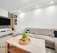 Living room in a three-room apartment with a corner sofa and a TV on the wall.