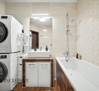 A bathroom with a bathtub, washing machine, dryer, and sink creates comfort in a 3-room apartment.