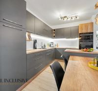 A kitchen in a 3-room apartment with dark cabinets and a wooden decor floor.