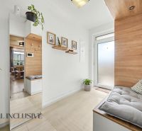 The entrance hall of a three-room apartment with a wooden decor floor and plants.