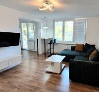 Living room of a two-room apartment with a wooden decor floor and a corner sofa.