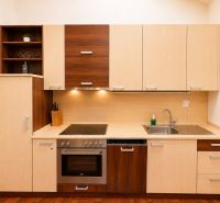 A kitchen in a 3-room apartment with a wooden decor floor, light furniture.