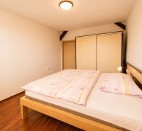 A bedroom in a 3-room apartment with a wood-patterned floor and a built-in wardrobe.