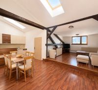 Living room with wood-patterned flooring and a kitchenette in a three-room apartment.