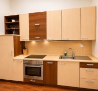 A kitchen in a 3-room apartment with wooden cabinets, a sink, and a cooktop.