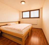 A bedroom with a bed and a wooden decor floor in a 3-room apartment.