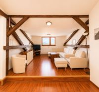 Attic living room with wooden beams and flooring with a wooden decor in a 3-room apartment.