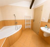 Bathroom in a 3-room apartment with a corner bathtub, sink, and ladder radiator.