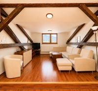 A stylish living room with a wood-patterned floor in a three-room apartment with roof beams.