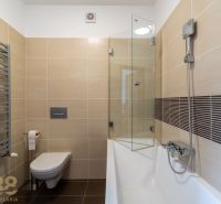 Bathroom in a holiday apartment with a bathtub, shower, and wall-hung toilet.