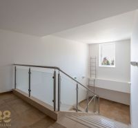 Interior of a staircase in a holiday apartment with wood-patterned flooring and a large window.