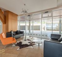 A recreational apartment with leather furniture, a glass wall, and wooden decor.