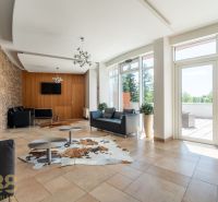 A recreational apartment with leather sofas, a stone wall, and large windows.