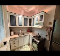 A kitchen in a 3-room apartment with a corner unit and a floor with a wood decor.