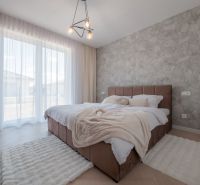 A bedroom with a stone wall, wood-patterned flooring, and a soft carpet in a family house.