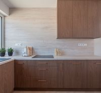 A kitchen in a family house with wooden decor cabinets and a large window.