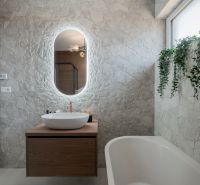 A bathroom in a family house with stone cladding, hanging plants, and a vessel sink.
