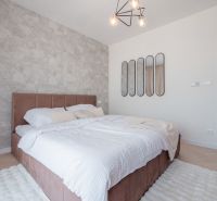 Bedroom of the house with a bed, mirrors, and a textured wall in cream shades.