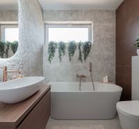 A modern bathroom in a family house with a bathtub, sink, toilet, and flowers.