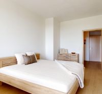 Bedroom with a bed, dresser, and wooden decor flooring in a two-room apartment.