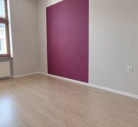 An office interior with wood-patterned flooring and a purple accent wall.