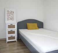 A bright bedroom with a blue curtain, white furniture, and decor in a two-room apartment.