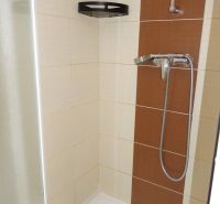 A shower corner with beige-brown tiles in a 2-room apartment.
