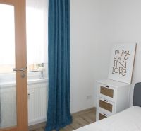 Interior of a 2-room apartment with white walls, curtains, and wooden doors.
