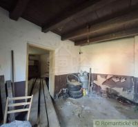 Room with building materials, barrels, and damaged walls in a family house.