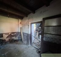 The interior of a family house with peeled walls and open doors leading outside.