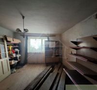 An unkempt room in a family house with wooden shelves and racks.