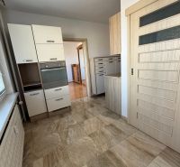 A kitchen in a 3-room apartment with tiles and light furniture.