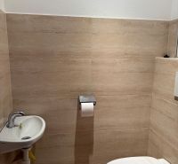 A bathroom in a 3-room apartment with beige tiles and a compact sink.