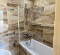 Bathroom with a bathtub and tiles with a natural decor in a 3-room apartment.