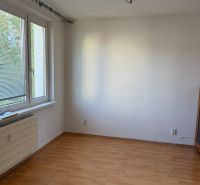 A room with white walls, windows, and a wooden decor floor in a 3-room apartment.