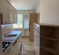 A kitchen in a 3-room apartment with tiles and light kitchen cabinets.