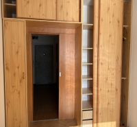Built-in wardrobe with shelves and doors in a 3-room apartment, floor with wooden decor.