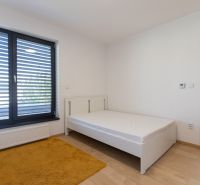 A bedroom in a 4-room apartment with a single bed, a yellow carpet, and a wooden decor floor.