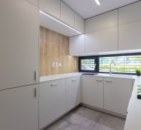 A kitchen in a 4-room apartment with a wooden decor floor, light furniture, and a large window.