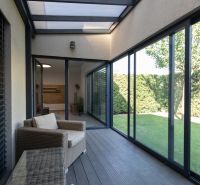 A glazed terrace with seating in a 4-room apartment and a view of the garden.