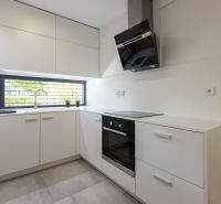 A kitchen in a 4-room apartment with white cabinets and a large window.