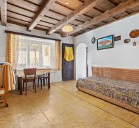 Interior of a family house with a wooden ceiling, bed, table, and chairs.