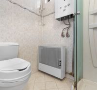 Toilet, shower corner, and gas heater in the bathroom of a family house.