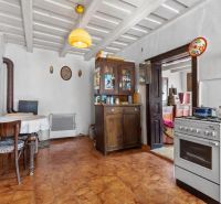 A kitchen in a family house with a stove, a cooker, and wooden furniture.