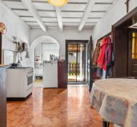 A kitchen in a family house with an arched doorway, a dining table, and a floor with a wooden design.