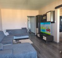 Living room with wood-patterned flooring and a large corner sofa in a 3-room apartment.