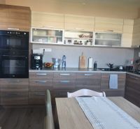 A kitchen in a 3-room apartment with a wooden decor floor, a dining table, and a kitchen unit.